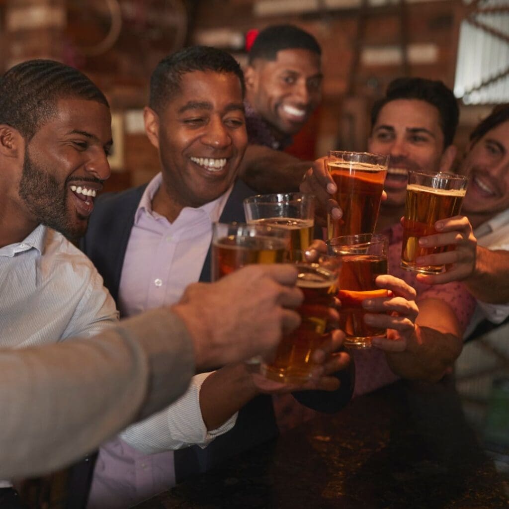 Bachelor party celebration at the pub with group cheering with wine glasses