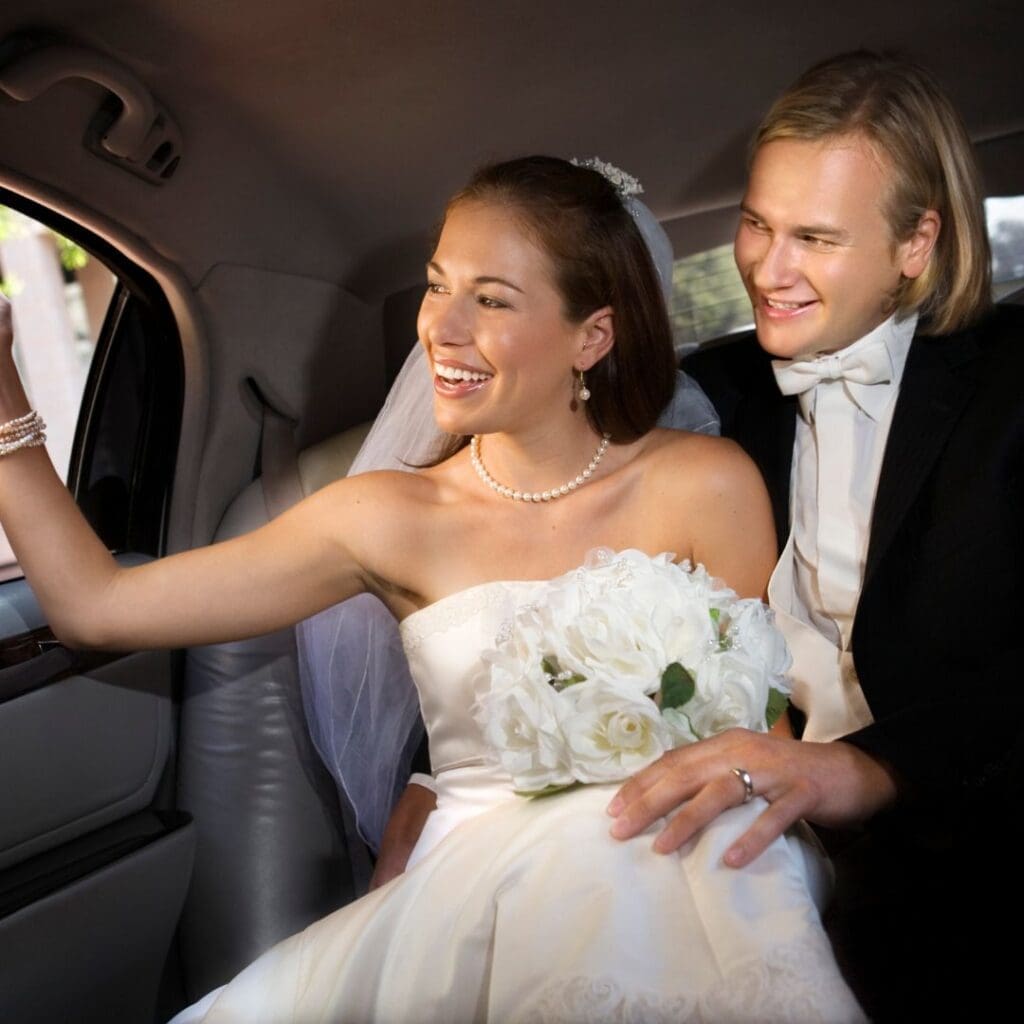 Wedding couple in a limo waving at the guests
